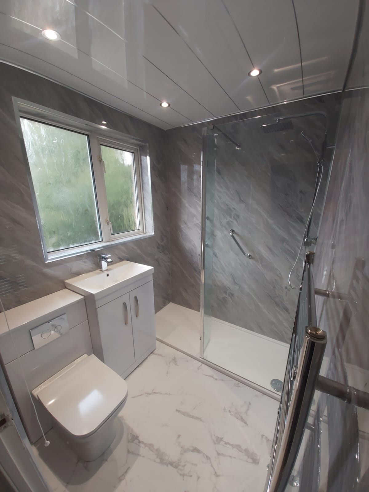 Grey marble-effect shower room with white furniture and chrome fittings
