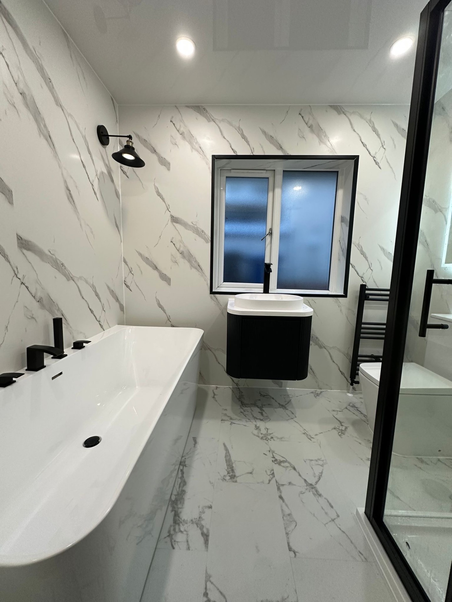 White marble bathroom with a freestanding bath and black fittings